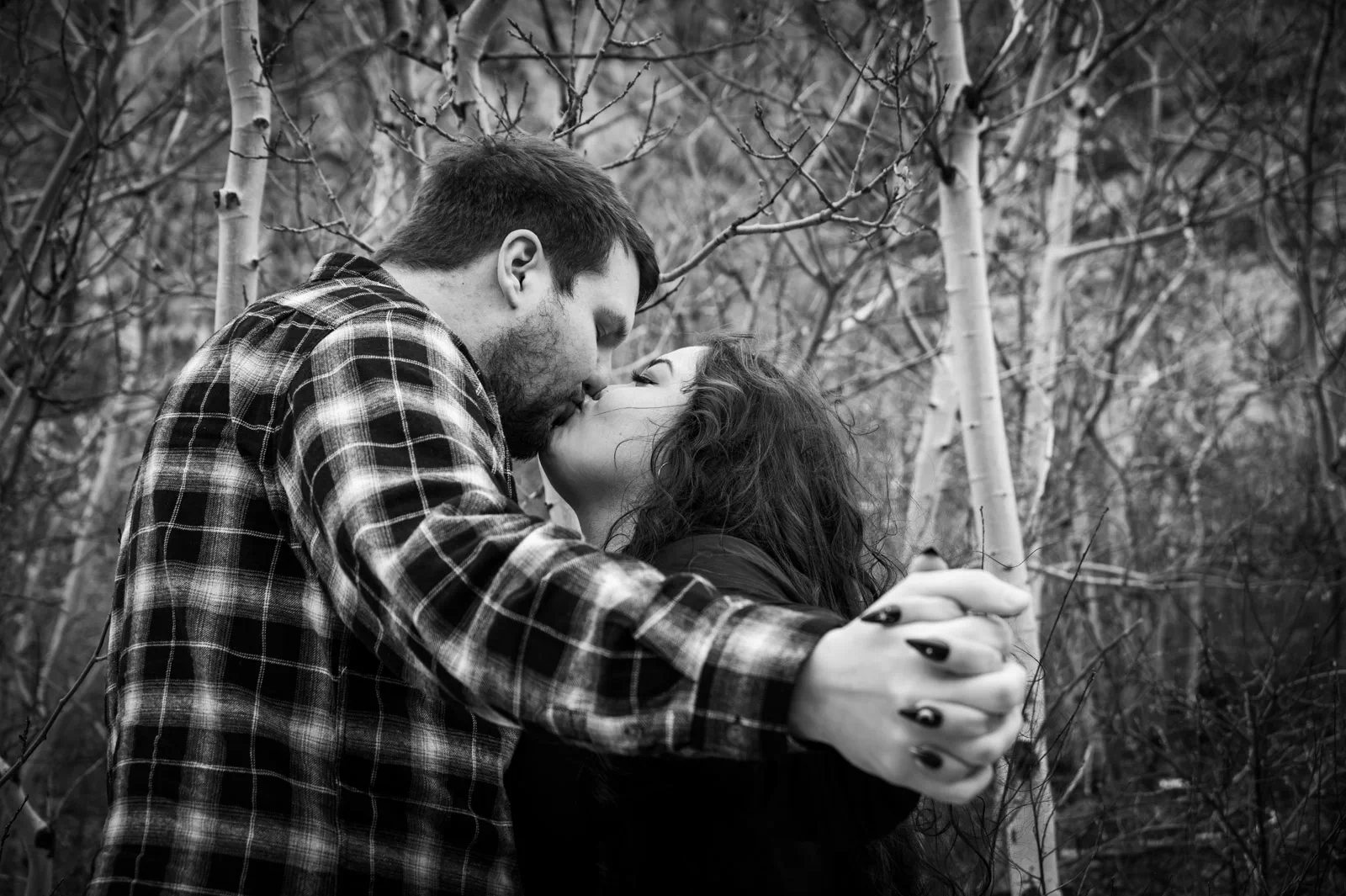Couple kissing for engagement photo in aspen trees