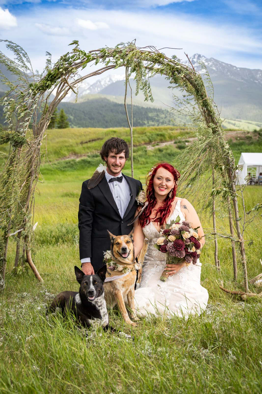 groom and bride under arch with dogs