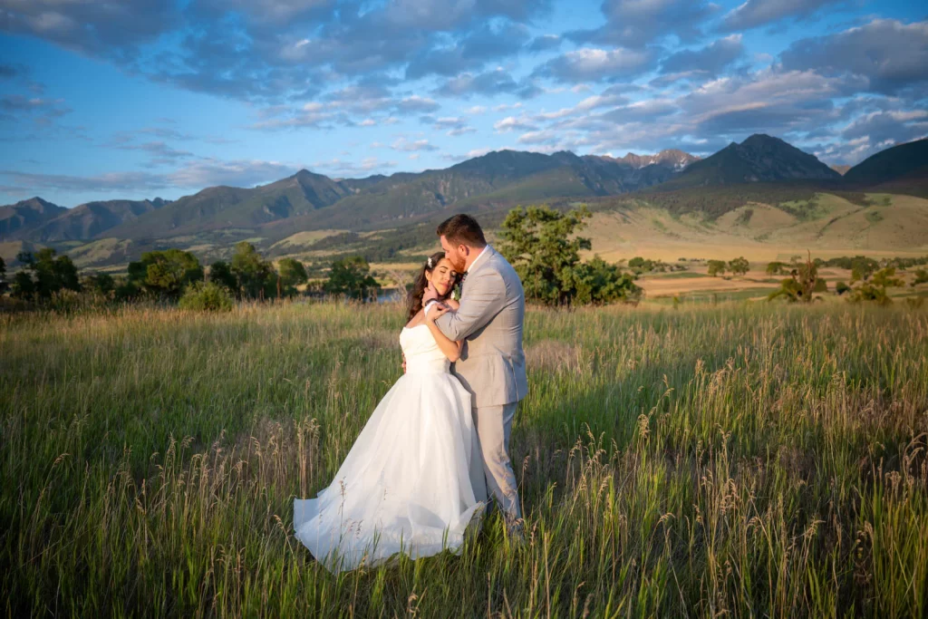 Bride and groom in a field Montana golden hour and Absaroka Mountains