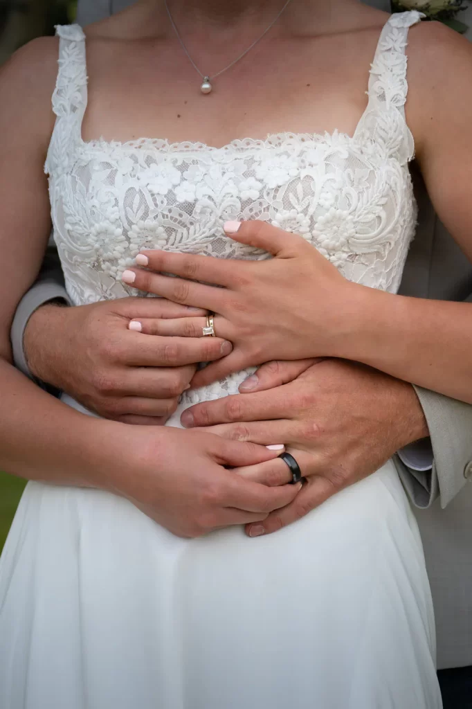 Bride and groom holding each others rings closeup